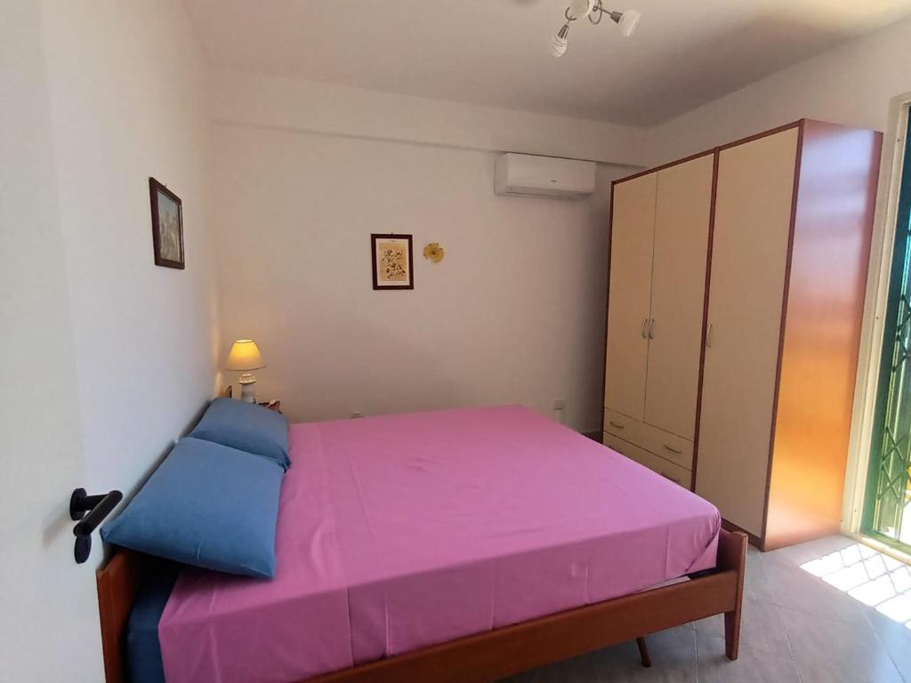 a bedroom with a pink bed and a cabinet at Blue Sea Apartment in Punta Braccetto