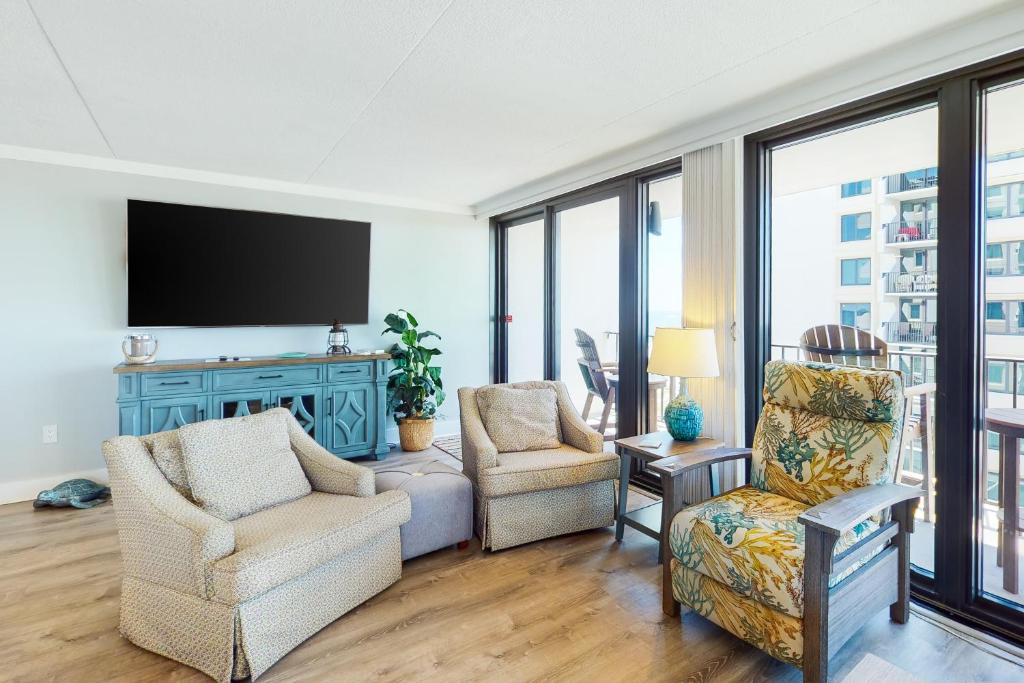 a living room with two chairs and a flat screen tv at Island Winds East 411 in Gulf Shores