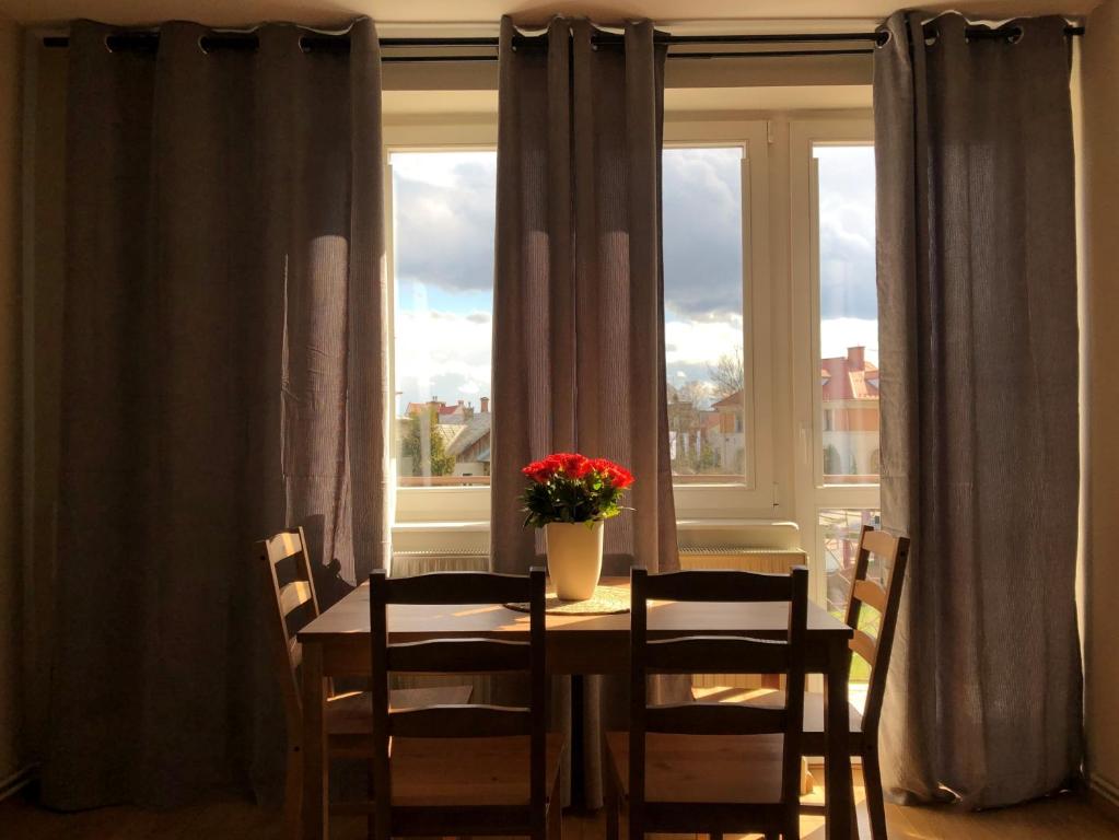 una mesa de comedor con sillas y un jarrón de flores en una ventana en Apartament Śródmieście Krosno en Krosno