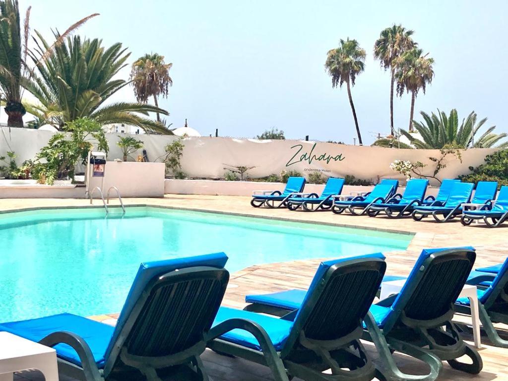a swimming pool with blue lounge chairs next to it at Apartament in Costa Adeje Playa de las Americas CasaNico in Playa de las Americas