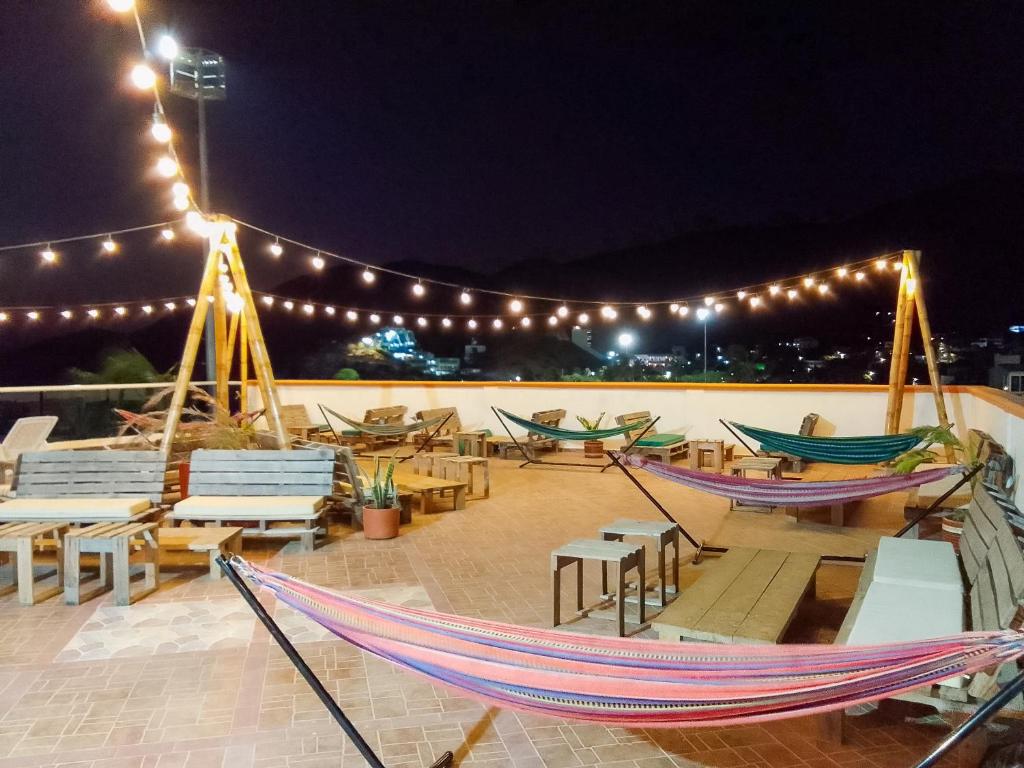 a patio with hammocks and tables and lights at night at Hostal Viña del Mar in Taganga