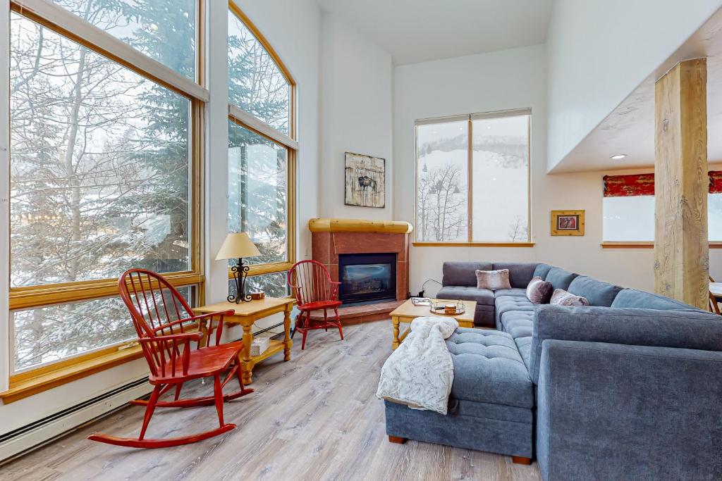 a living room with a blue couch and chairs and windows at Spruce Way Retreat in Vail
