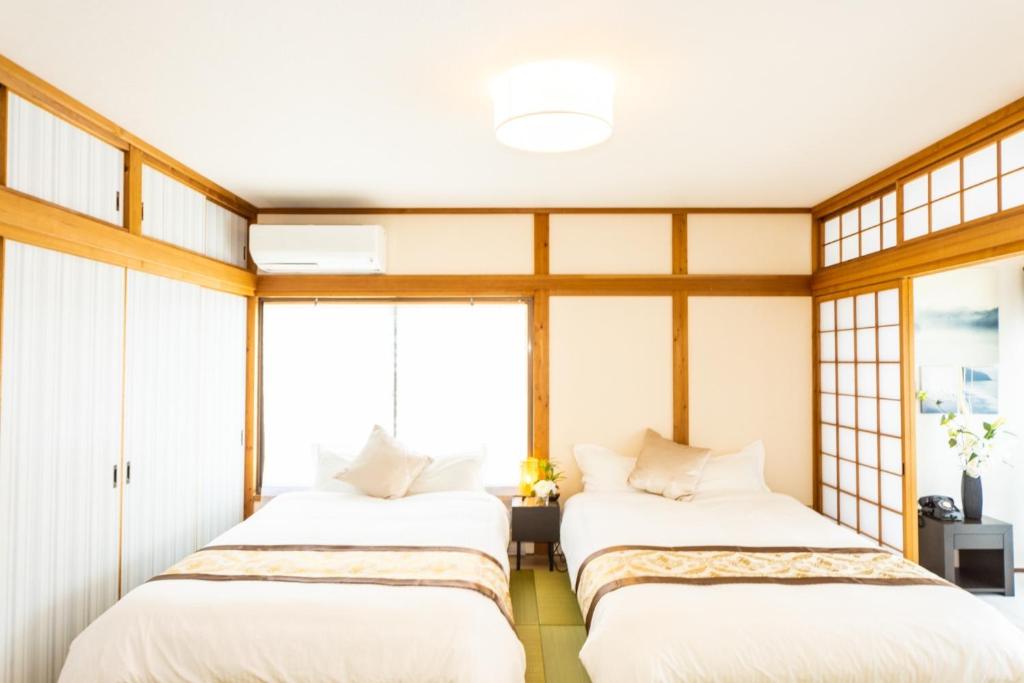 two beds in a room with windows at Ａｗａｊｉ Ｓｅａｓｉｄｅ Ｖｉｌｌａ ｉｎ Ｇｏｓｈｉｋｉ - Vacation STAY 98416v in Sumoto