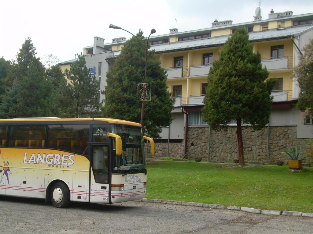 a yellow bus parked in front of a building at DW Potok in Wisła