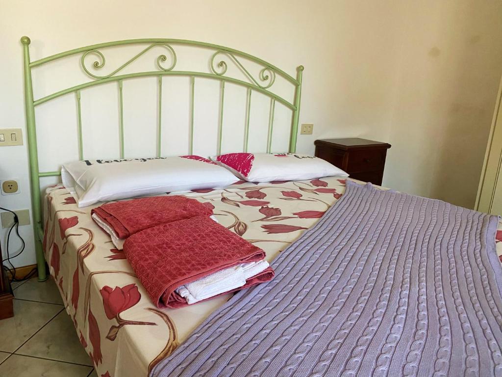 Una cama con almohadas rojas encima. en Aria di casa affittacamere, en Badesse