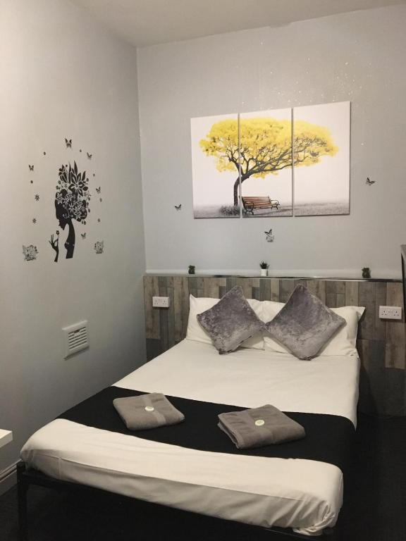 a bedroom with a bed with two paintings on the wall at Queens Guesthouse Manchester in Manchester