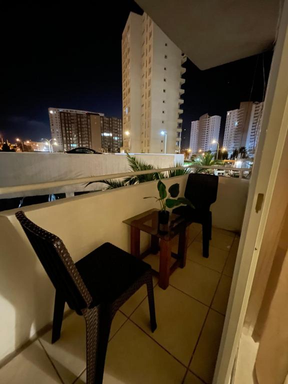 a balcony with chairs and a table at night at Departamento Amoblado 3 Habitaciones in Coquimbo
