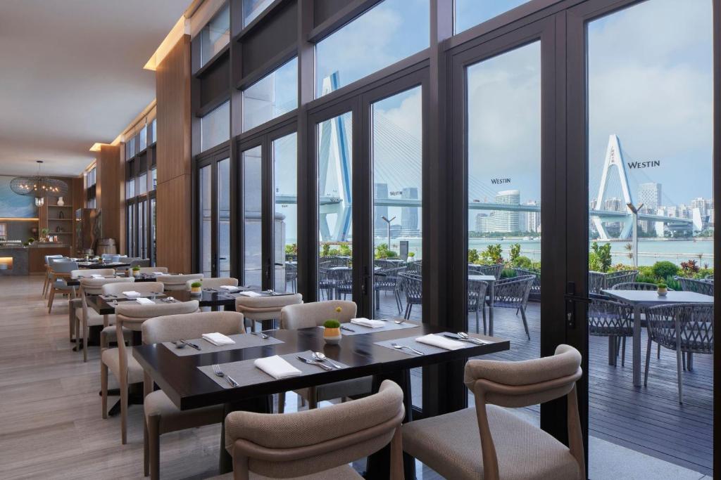 a restaurant with tables and chairs and a view of the city at The Westin Haikou in Haikou