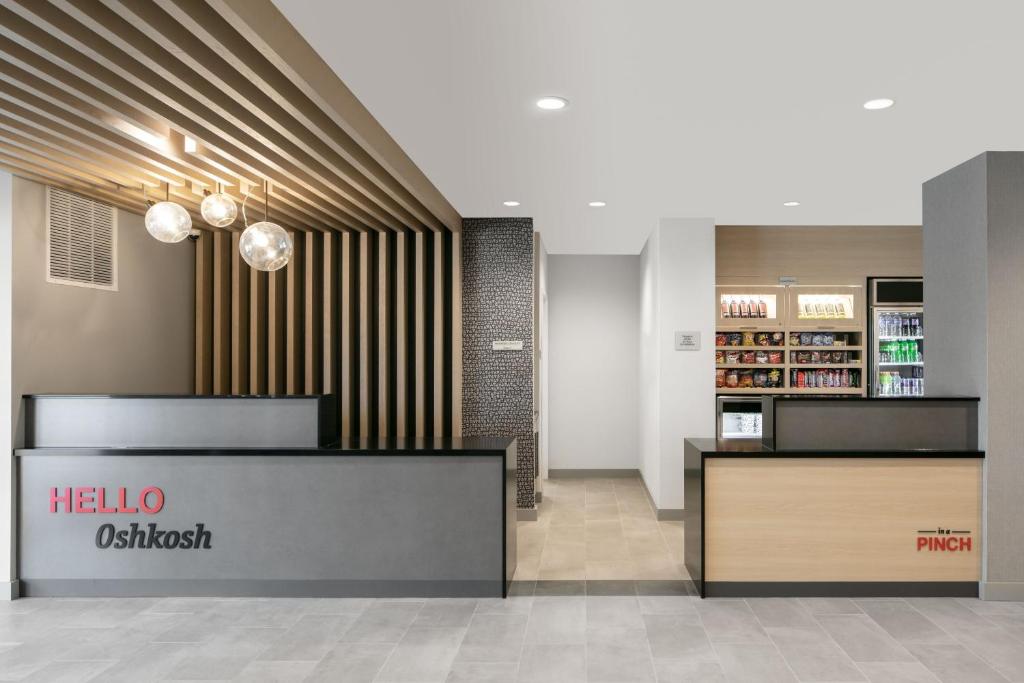 a lobby of a store with ahiwaossitz sign on the wall at TownePlace Suites by Marriott Oshkosh in Oshkosh