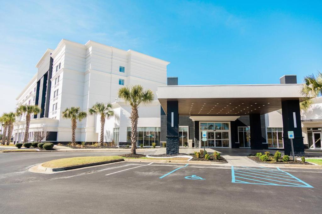 a large white building with palm trees in a parking lot at Delta Hotels Columbia Northeast in Columbia