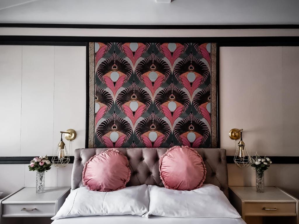 a bedroom with a large headboard with pink pillows at GARDENIA in Jelenia Góra