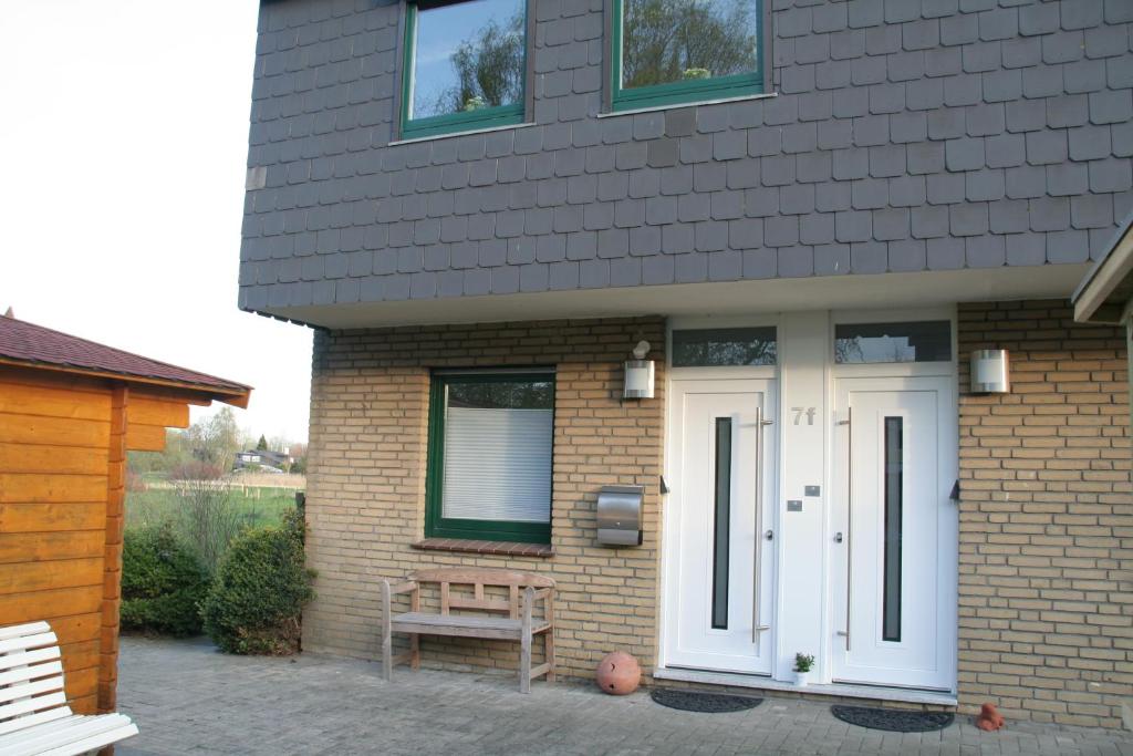 a house with a white door and a wooden bench at FeWo Seeluft - Hooksiel in Wangerland