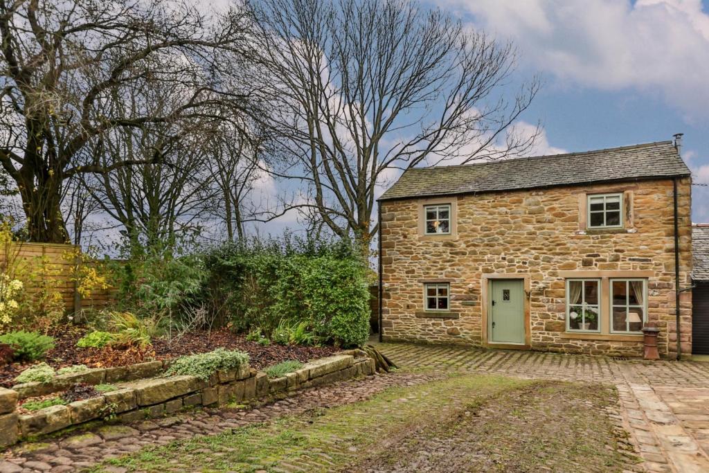 a stone house with a green door in a garden at Finest Retreats - Middle Warble Stables in Mellor