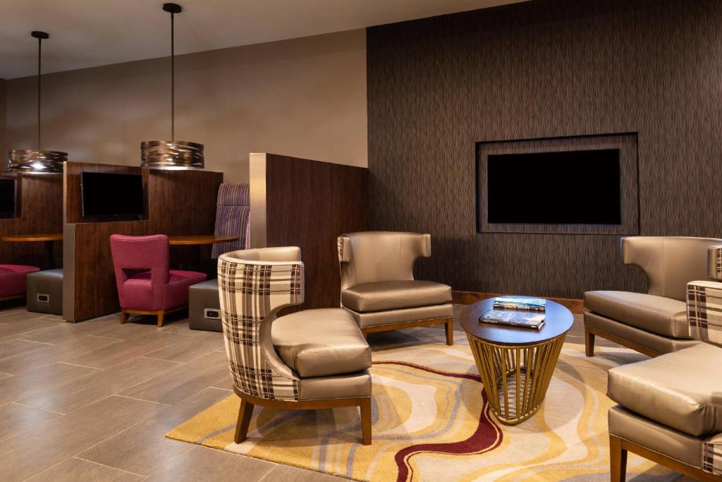a lobby with chairs and a table and a tv at Courtyard by Marriott Charlotte Northlake in Charlotte