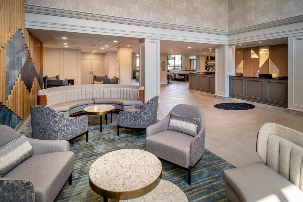 a lobby with couches chairs and tables and a kitchen at Delta Hotels Huntington Downtown in Huntington
