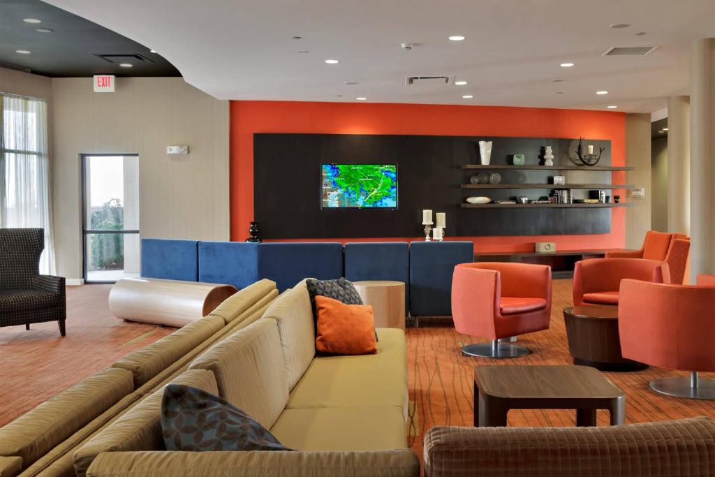 a living room with a couch and a flat screen tv at Courtyard by Marriott Harrisburg Hershey in Harrisburg