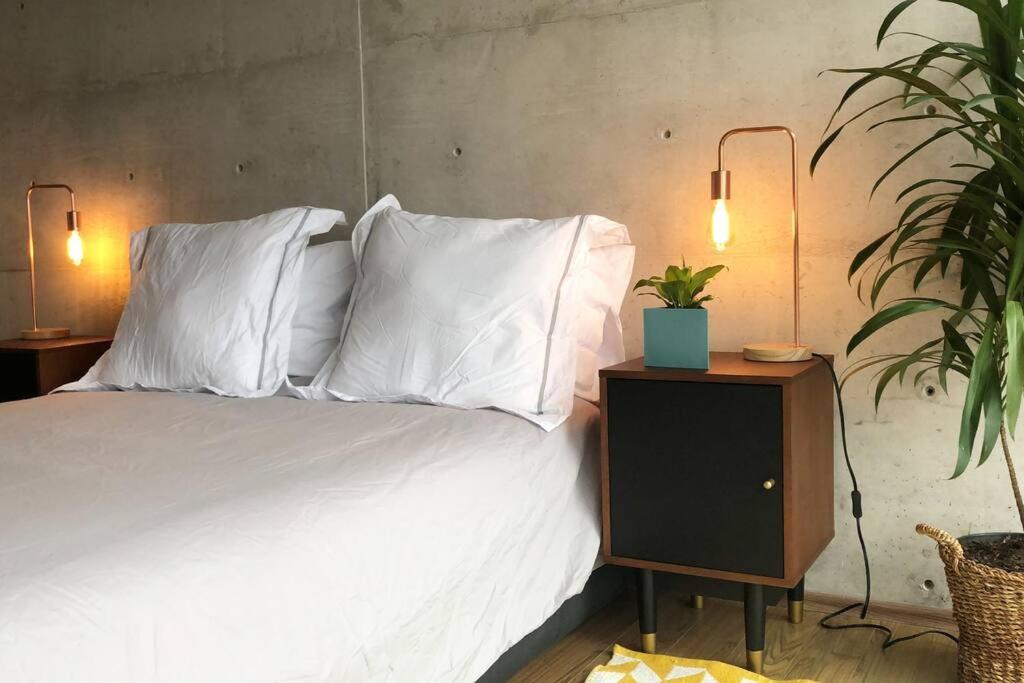 1 dormitorio con 1 cama con sábanas y almohadas blancas en Super cool & comfortable in the heart of Condesa., en Ciudad de México