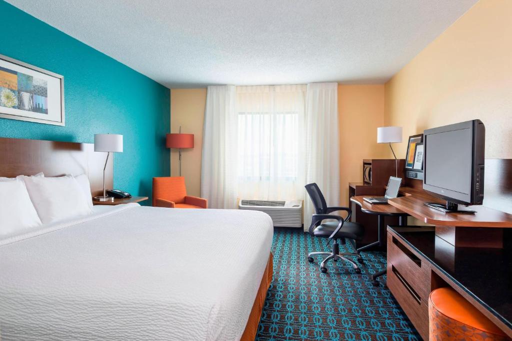 a hotel room with a bed and a desk with a computer at Fairfield Inn & Suites Springfield in Springfield