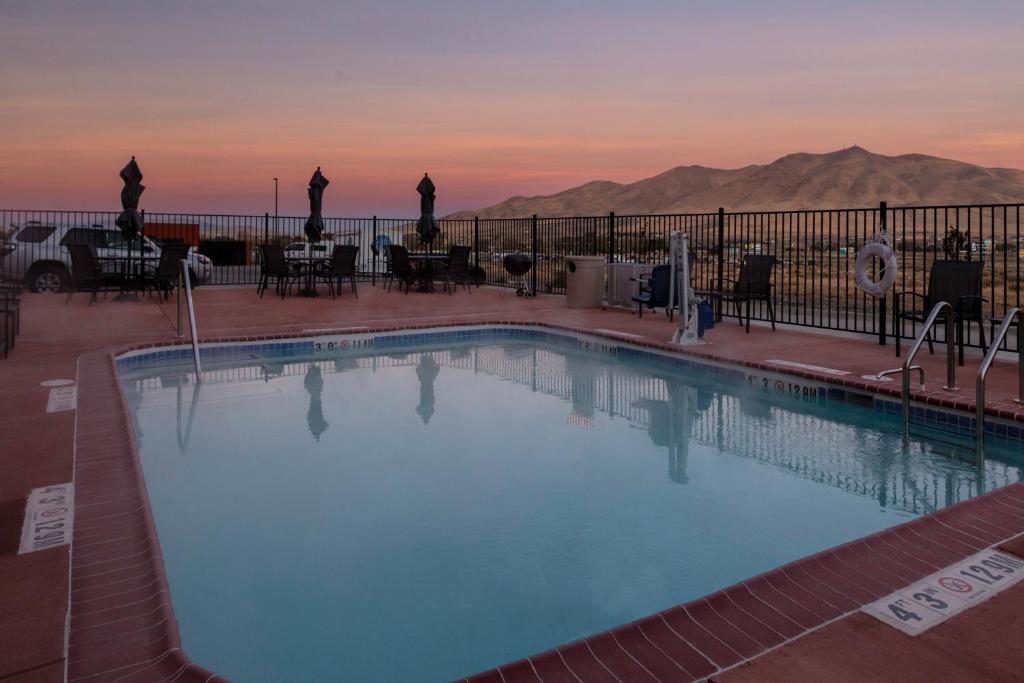 Fairfield Inn & Suites by Marriott Winnemucca في وينيموكا: مسبح مع غروب الشمس في الخلفية