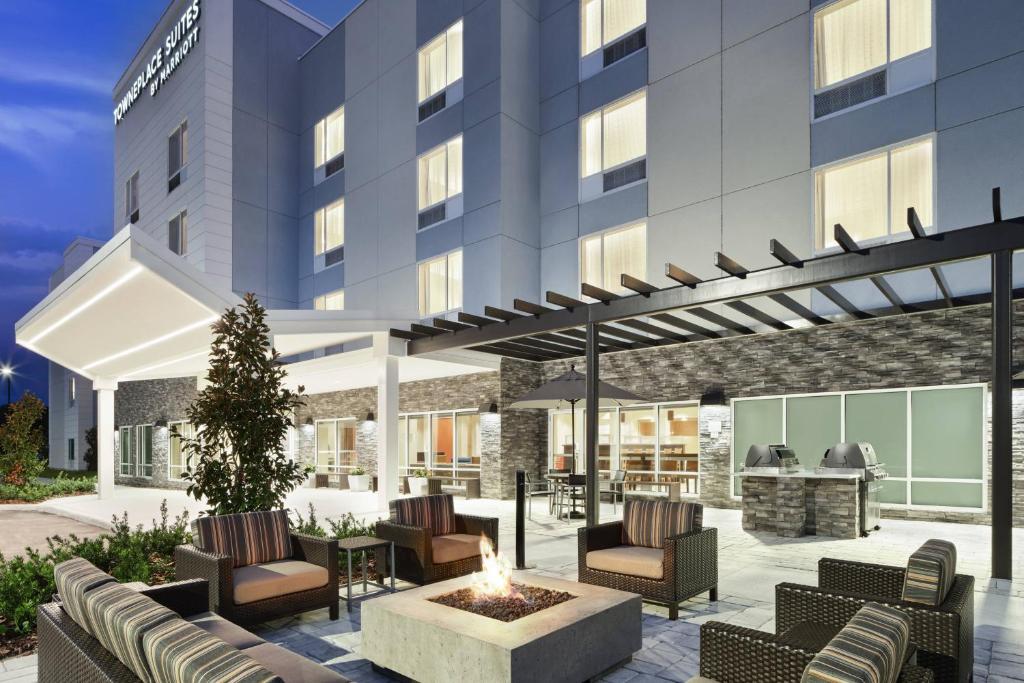 une terrasse avec des chaises et un foyer extérieur en face d'un bâtiment dans l'établissement TownePlace Suites by Marriott Leesburg, à Leesburg