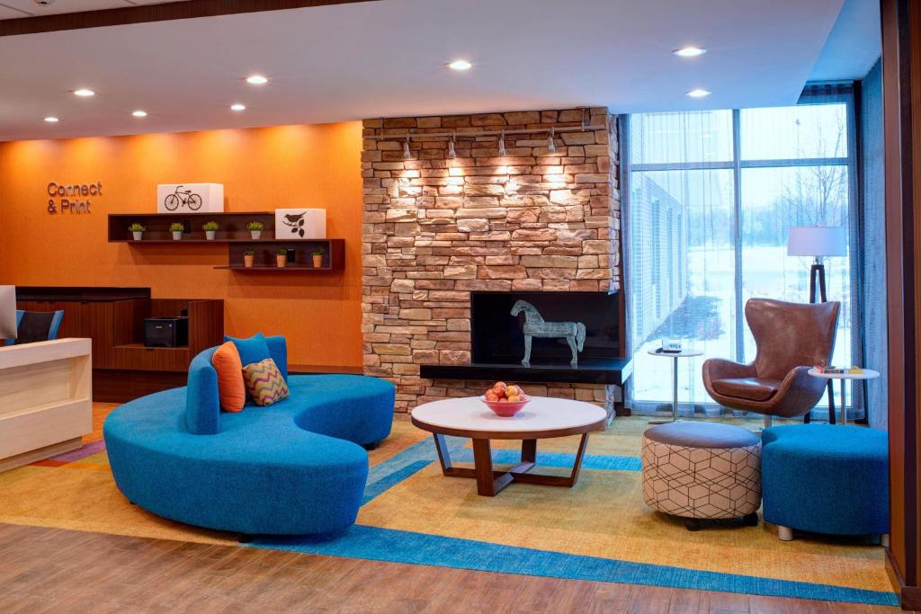 Fairfield Inn & Suites By Marriott Ann Arbor Ypsilanti في إبسيلانتي: غرفة معيشة مع كراسي زرقاء ومدفأة