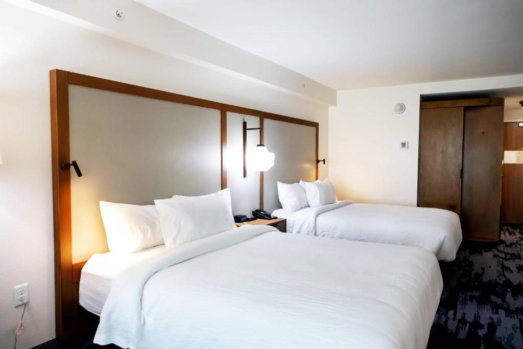 duas camas num quarto de hotel com lençóis brancos em Fairfield by Marriott Inn & Suites Louisville Airport em Louisville