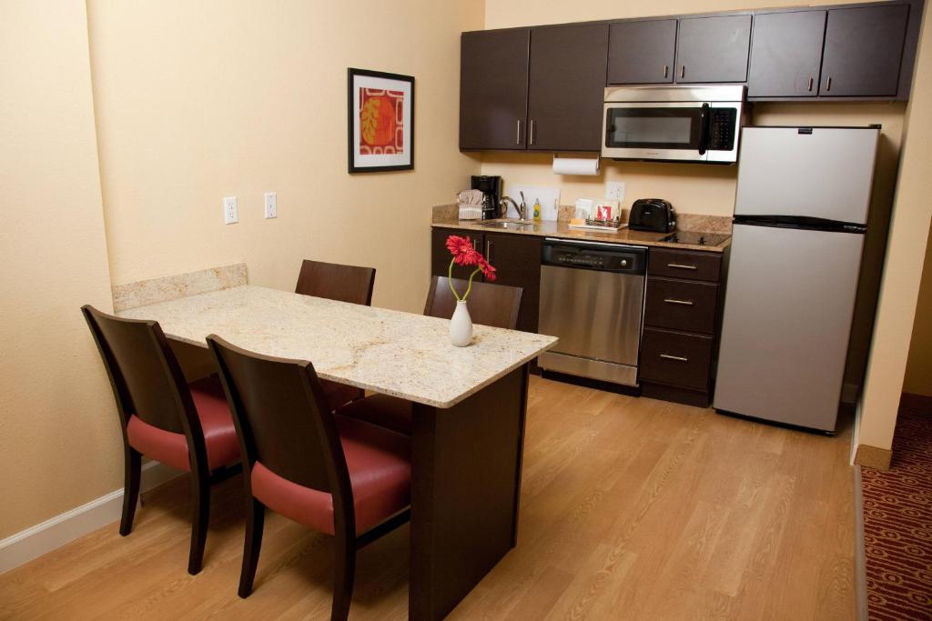 y cocina con mesa, sillas y nevera. en TownePlace Suites by Marriott Lake Jackson Clute, en Clute