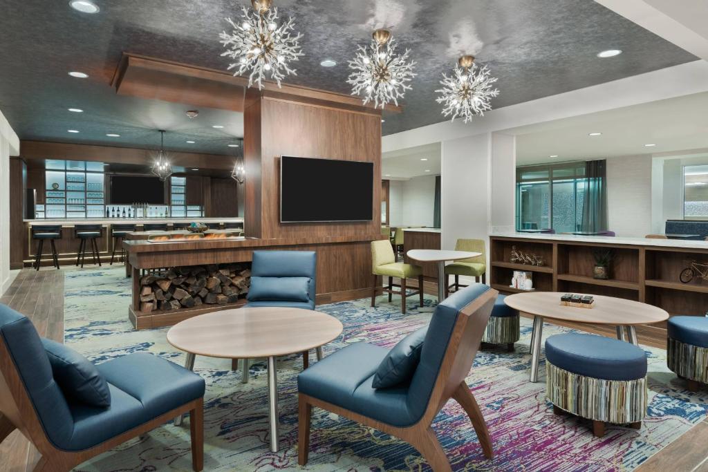 a lobby with tables and chairs and a flat screen tv at Residence Inn by Marriott Buffalo Downtown in Buffalo