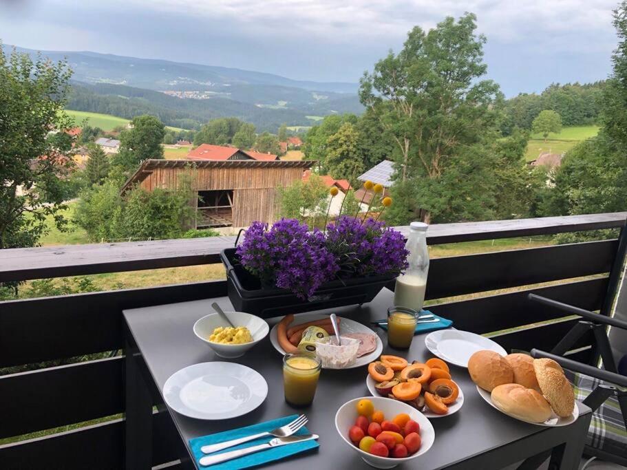 une table avec des assiettes de nourriture sur un balcon dans l'établissement Apartment Tälerblick Maxi -neu modernisiert-, à Böbrach