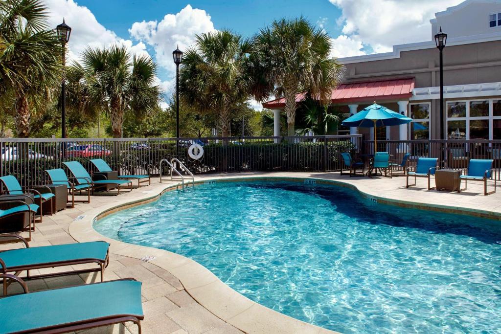 einen Pool mit Stühlen und Sonnenschirmen in einem Resort in der Unterkunft Residence Inn Tampa Suncoast Parkway at NorthPointe Village in Lutz