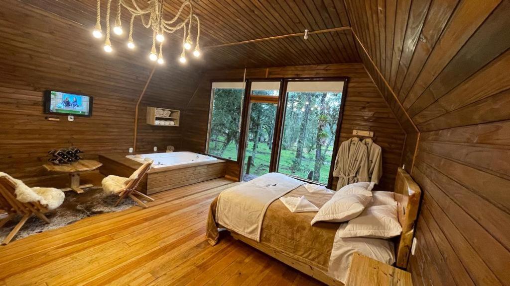 a bedroom with a bed and a tub in a room at Cabana Paradouro da Serra in Cambara do Sul