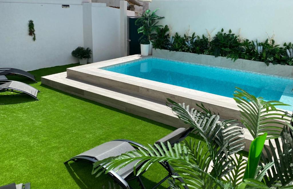 una piscina en un patio trasero con césped verde en Esencia Andalucia en Rociana