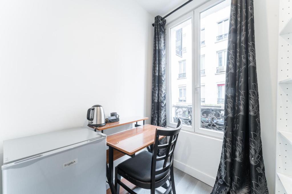 a small table and chair in a small room with a window at L&#39;Oasis Montparnasse in Paris