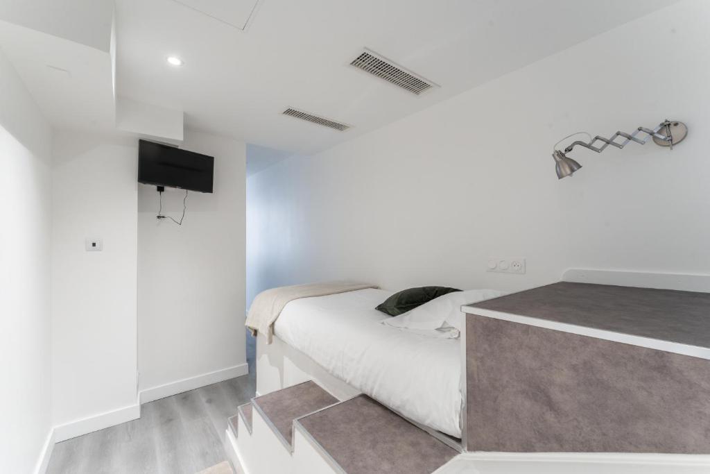 a white bedroom with a bed and a tv at L&#39;Oasis Montparnasse in Paris