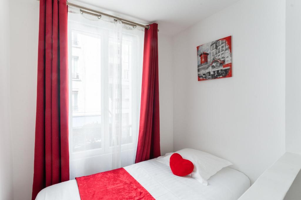 a bedroom with a red window with a red heart pillow at L&#39;Oasis Montparnasse in Paris
