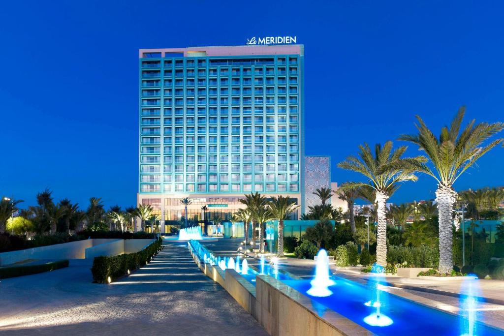 a tall building with palm trees in front of it at Le Meridien Oran Hotel in Oran
