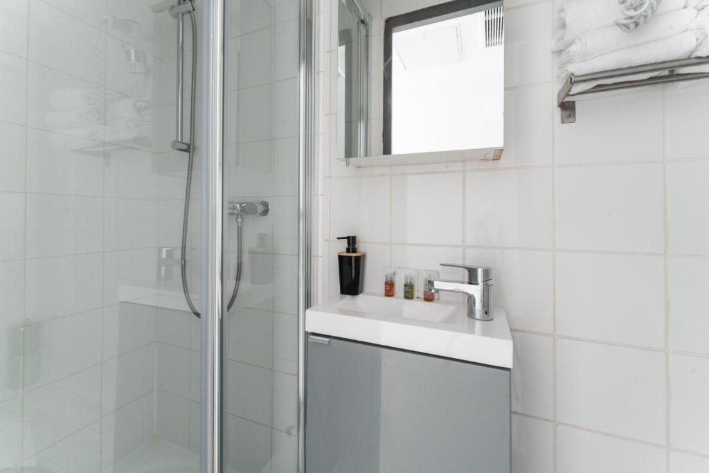 a white bathroom with a shower and a sink at L&#39;Oasis Montparnasse in Paris