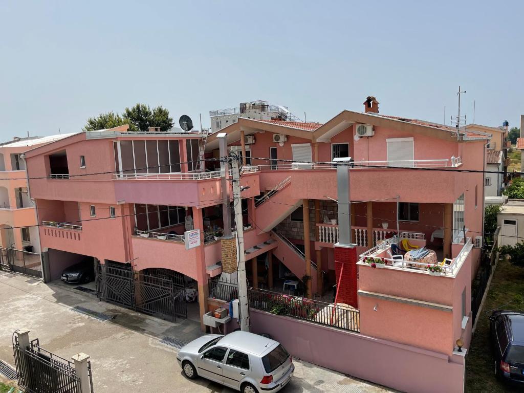 een roze gebouw met een auto ervoor geparkeerd bij Apartments Zeneva in Donji Štoj