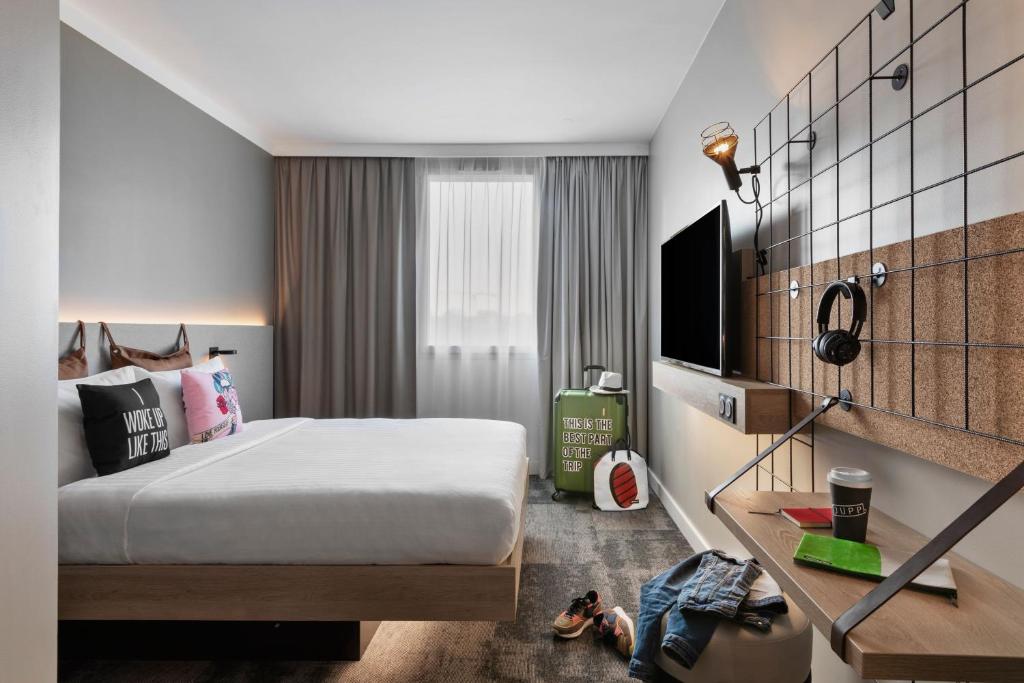 ein Hotelzimmer mit einem Bett und einem TV in der Unterkunft Moxy Amiens in Amiens