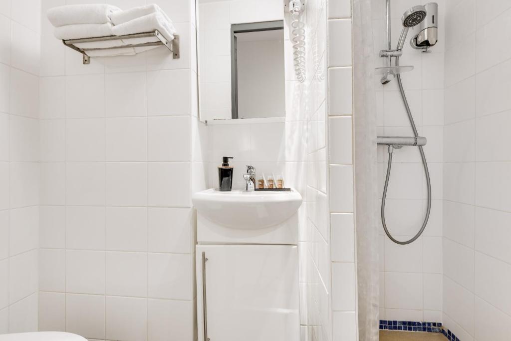 a white bathroom with a sink and a shower at L&#39;Oasis Montparnasse in Paris