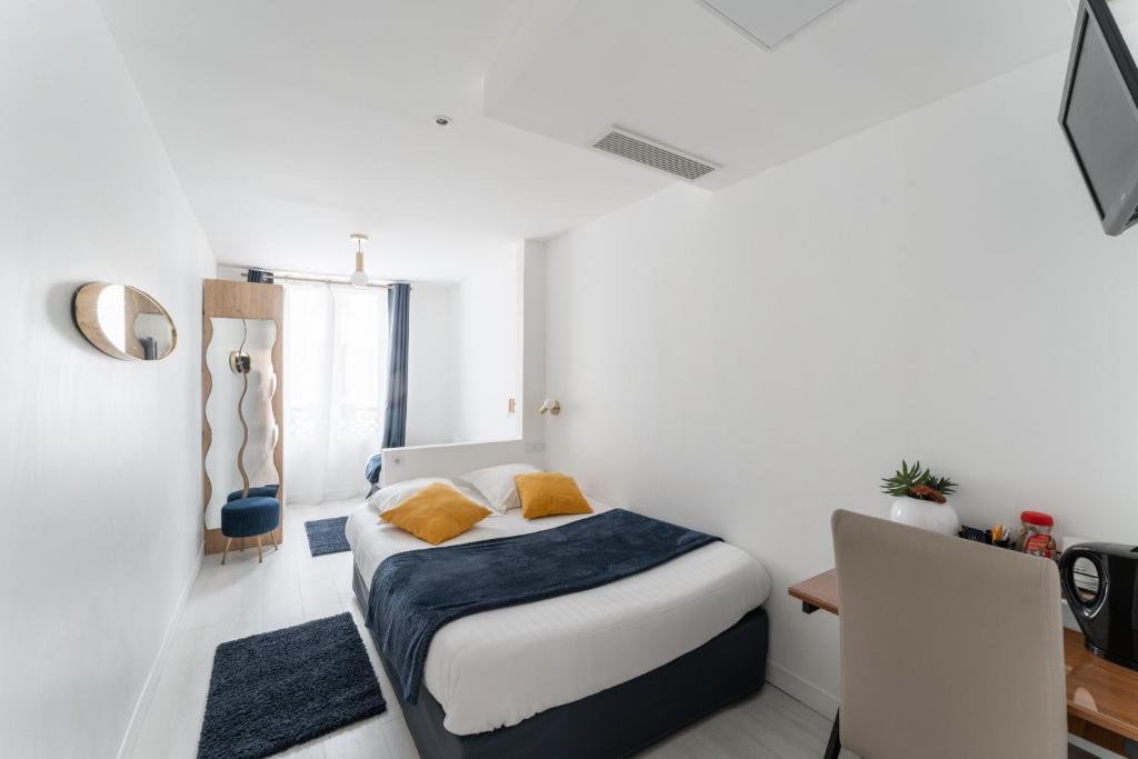 a white bedroom with a bed and a desk at L&#39;Oasis Montparnasse in Paris