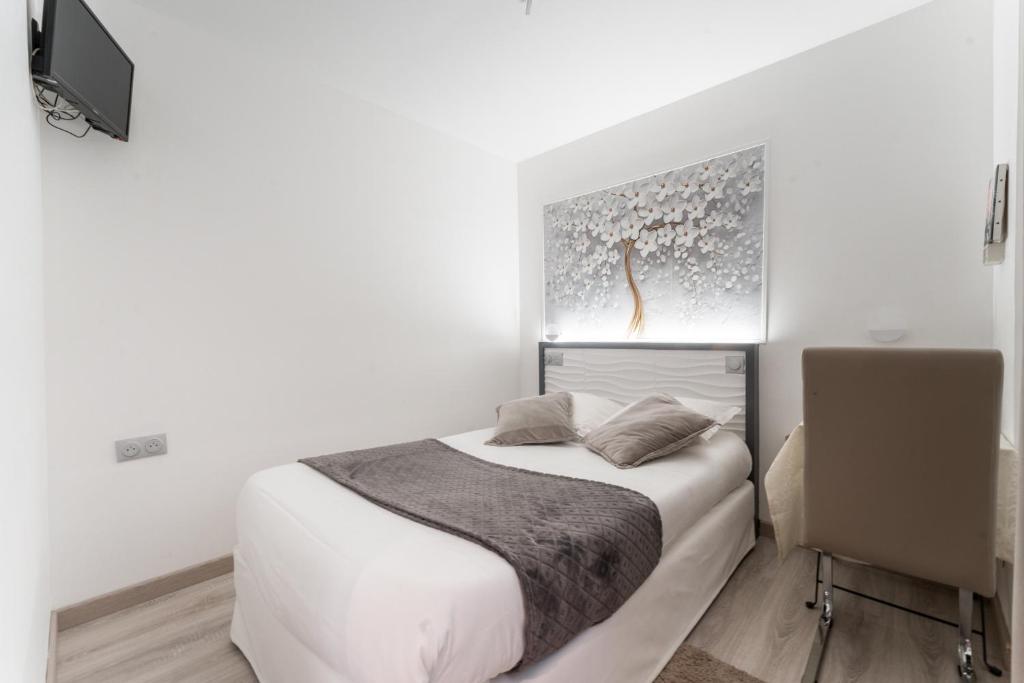 a white bedroom with a bed and a television at L&#39;Oasis Montparnasse in Paris