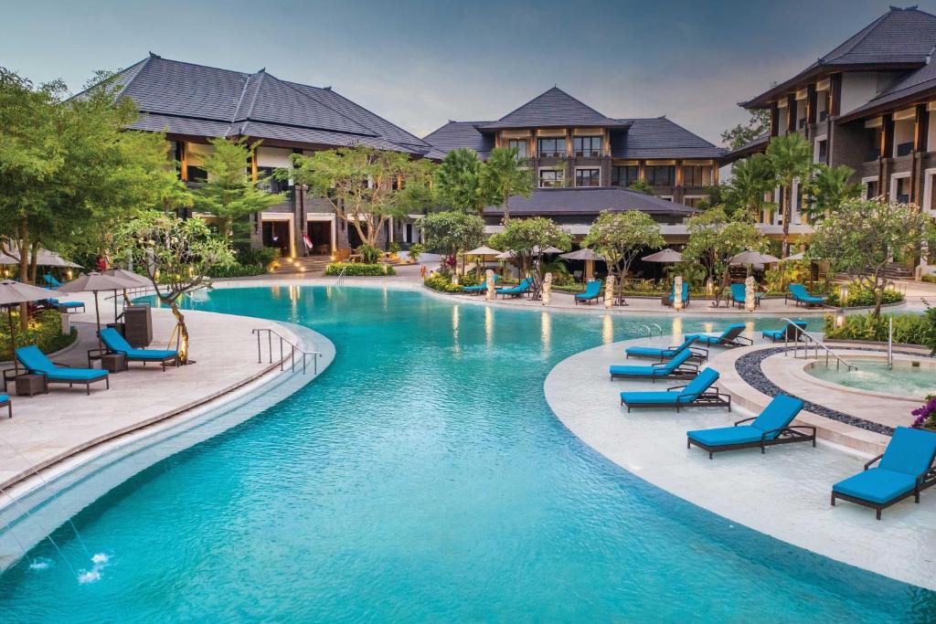 a pool at a resort with blue chairs and buildings at Marriott’s Bali Nusa Dua Gardens in Nusa Dua