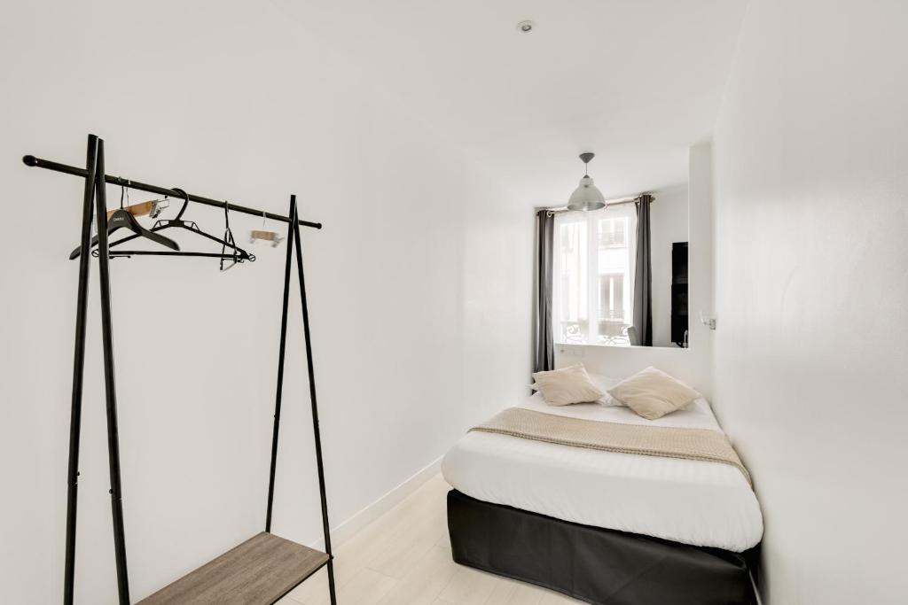 a white bedroom with a bed and a mirror at L&#39;Oasis Montparnasse in Paris