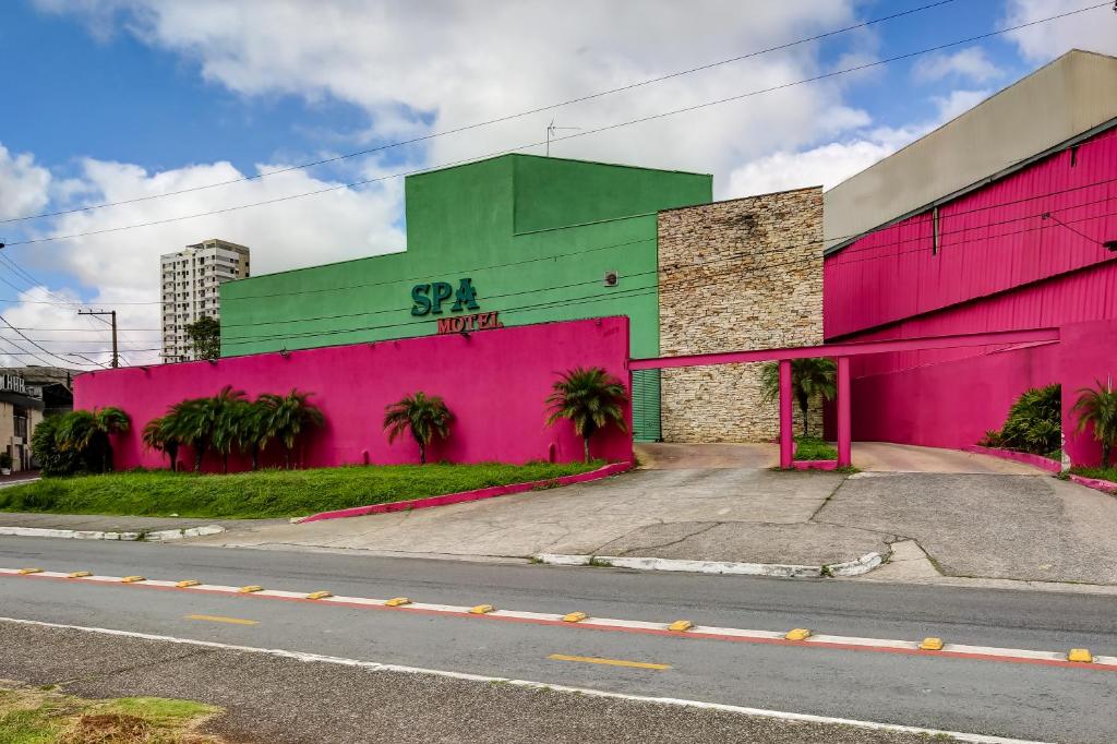 un bâtiment rose et vert sur le côté d'une rue dans l'établissement Spa Motel - Radial Leste, à São Paulo