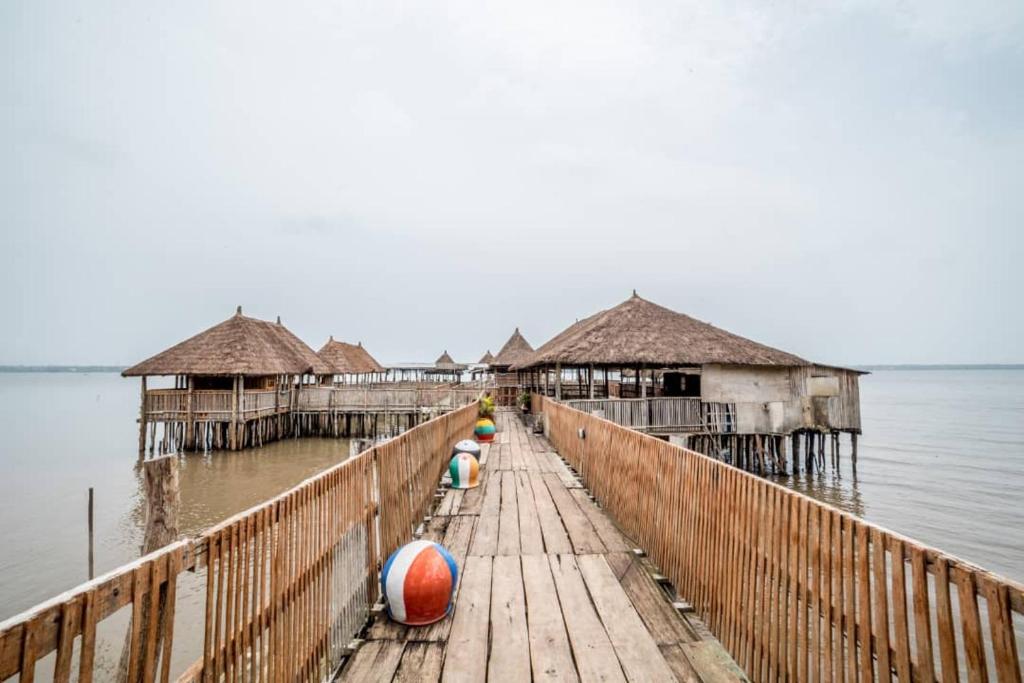 a wooden pier with huts on the water at Hotel Restaurant Chez Theo in Bopa