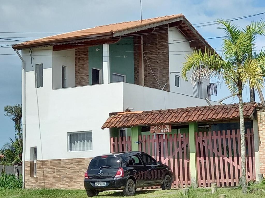 a black car parked in front of a house at Casa simples e aconchegante em Boracéia Bertioga SP in Bertioga