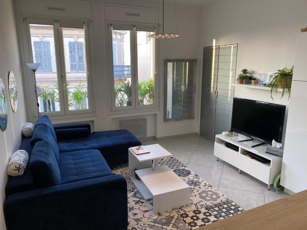 uma sala de estar com um sofá azul e uma televisão em Appartement Key West à Saint Raphaël em Saint-Raphaël