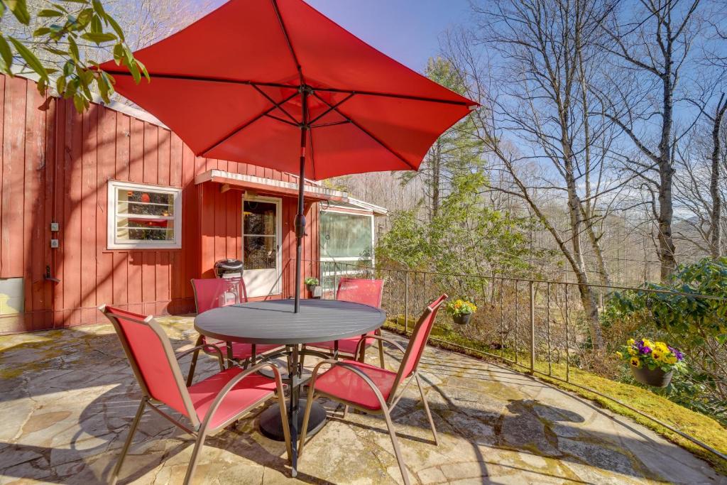 een tafel met stoelen en een rode parasol op een patio bij The Red Loft Candler Cottage 18 Mi to Asheville! in Candler