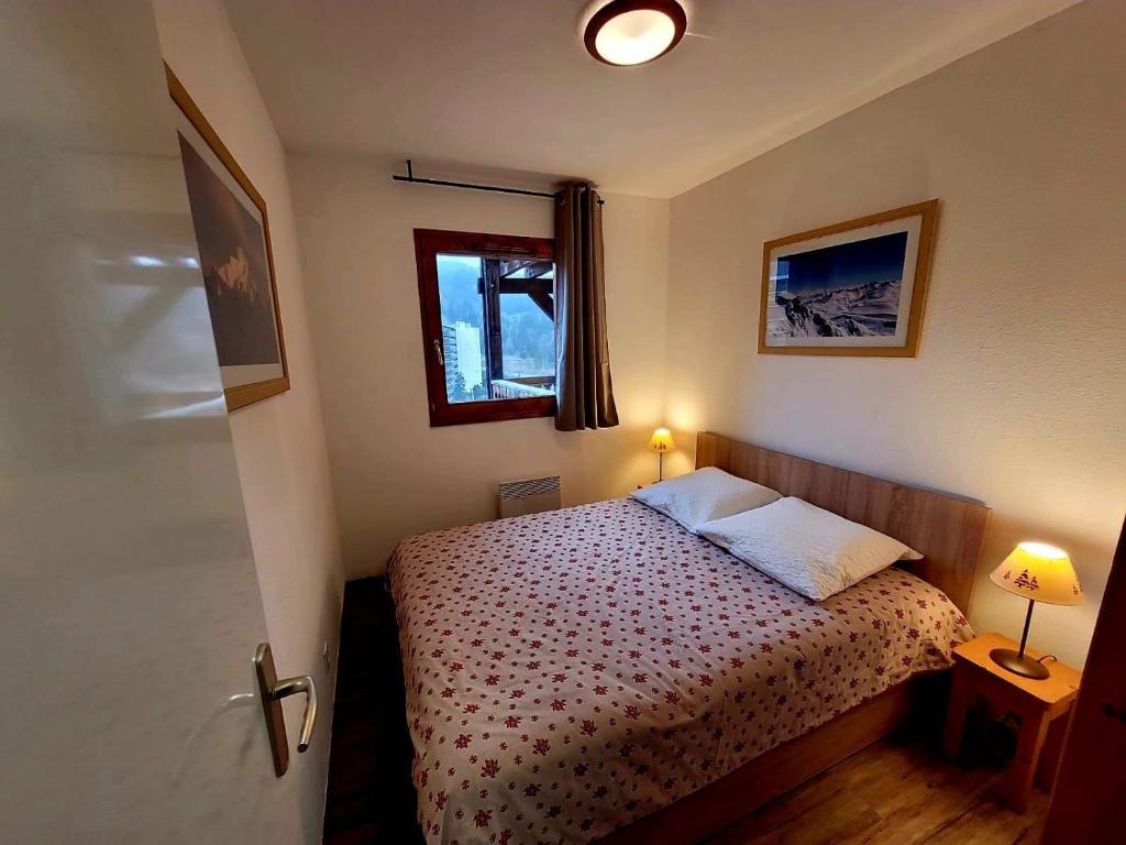 een kleine slaapkamer met een bed en een raam bij appartement t2 cosy 4 à 6personnes la gentiane in Superdevoluy